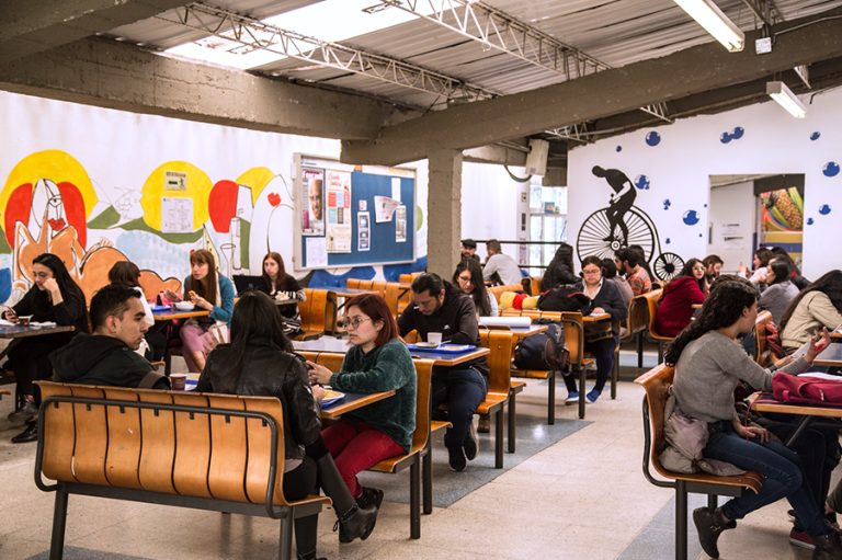 Fotografía de diferentes miembros de la comunidad pedagógica compartiendo en el espacio de la cafetería de la sede Calle 72